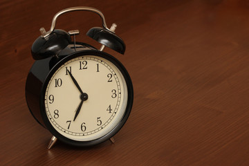 Old fashioned alarm clock on a wood background set to 7 am