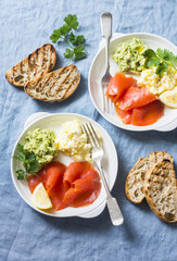 Two plates of breakfast or snack - egg salad, salmon and avocado puree on a blue background, top view. Healthy food concept