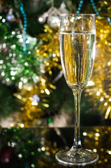 a glass of champagne on the background of a new-year tree