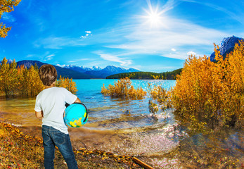 Boy in jeans with a globe