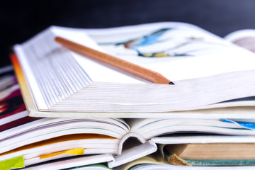 Open hardback and textbook stacked on the table on blackboard background.