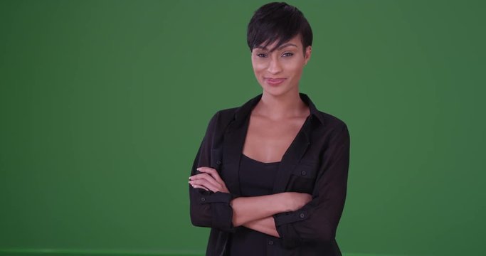 Young black woman in black casual wear cracks a smile at the camera on green screen. On green screen to be key or composited.