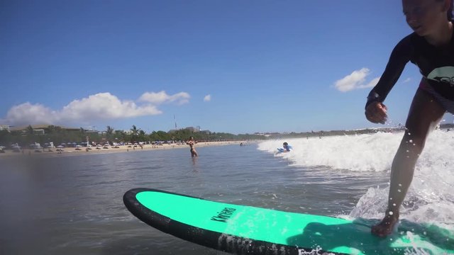 Young girl surfing in the ocean and having fun. Teenage girl in a surfing on the beah Kuta in Bali. Surfer with surf board. Lifestyle, people water sport adventure camp, beach extreme swim on summer