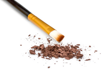 Makeup brush with crushed eye shadows on white background.