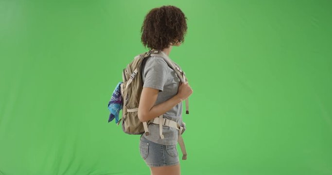 Young black millennial woman looks around and smiles at the camera on green screen. On green screen to be keyed or composited. 