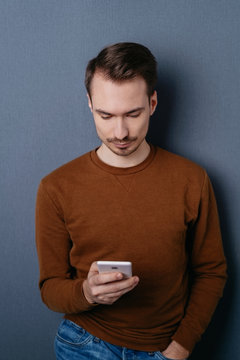 Young man standing reading a text message