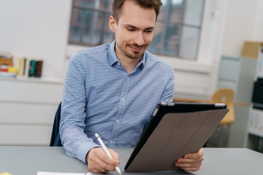 Smiling man sitting looking at a digital tablet