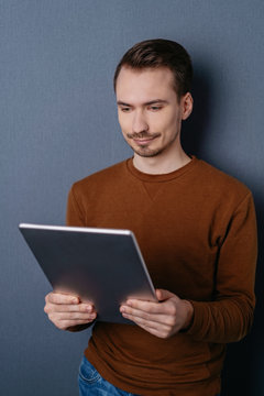 Man using digital tablet against dark wall