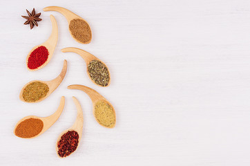 Multicolored asian spices in quaint spoons on white wooden background, as decorative christmas tree. Top view.