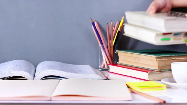 Women hand placed hardback books and textbooks stacked on the wooden table. The concept of intelligence comes from education. focused on textbook,