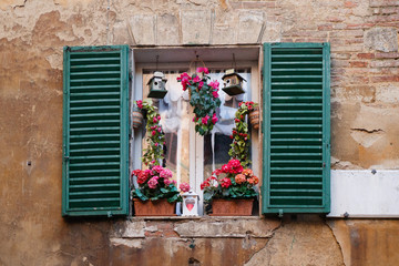Fototapeta na wymiar Characteristic window with flowerpot and decorations in Siena, Tuscany