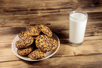 Chocolate chip cookies and glass of milk on wooden table