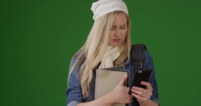 Portrait of hipster girl texting answers to social studies midterm on green screen. On green screen to be keyed or composited.