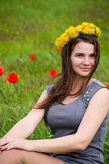 Beautiful fairy young girl in a field among the flowers of tulips. Portrait of a girl on a background of red flowers and a green field. Field of tulips.