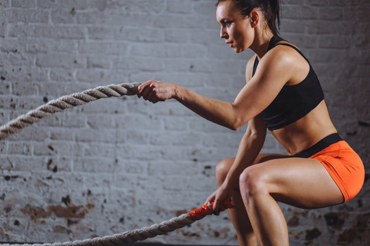 close up photo of Athletic woman doing battle rope exercises at gym