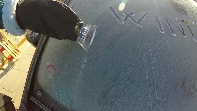 Frosted glass on the car.
Removing ice from the car windscreen using scraper. Winter weather and car trouble.
