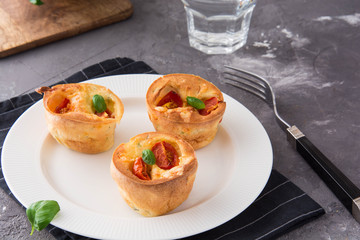 Salty snack. Homemade muffins with cheese, tomatoes and basil.