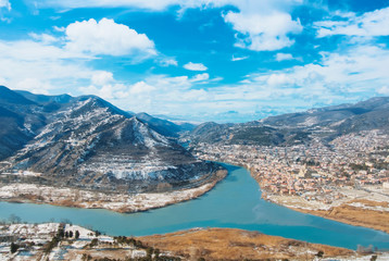 Iconic aerial panoramic top view to old ancient georgian town Mtskheta at the confluence of two rivers Mtkvari And Aragvi, winter mountain landscape, concept of travel and adventures at Caucasus.