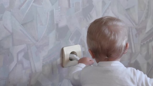 funny cute 9-10 months old baby pulls out the plug from power socket