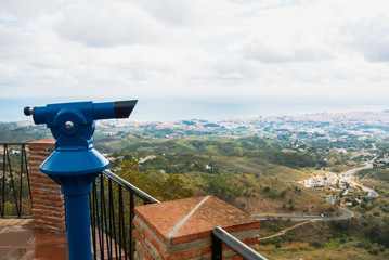 View point in the park of Mijas, a blue coin telescope and a beautiful panoramic aerial view to Mediterranean sea and a road to Fuengirola town on winter cloudy day, Andalusia, Spain.