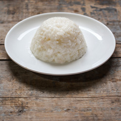 boiled round rice on a white plate, on a wooden surface