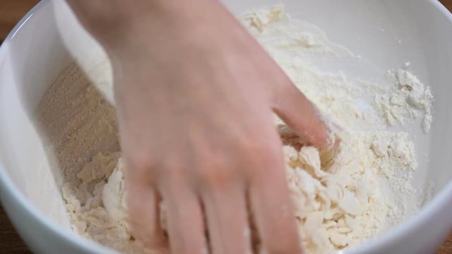 Women's hands knead the dough in the bowl