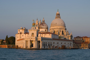 Fototapeta na wymiar The old building of the city customs of Dogana di Mar and the Cathedral of Santa Maria della Salute in the early morning. Venice