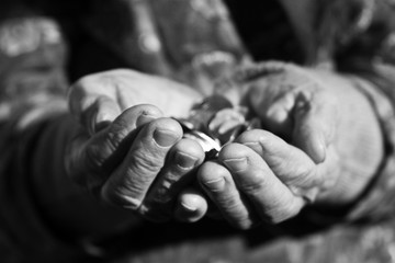 Black and white photo of coins in old wrinkled hands close-up