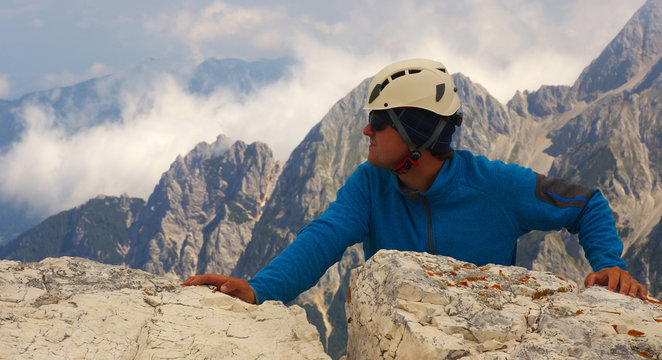 Climber leaning against a rock with a mountain landscape on bacground, Triglav National Park, Slovenia