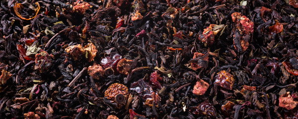 Food background with black tea, strawberry pieces and rose blossom with copy space. Selective focus.