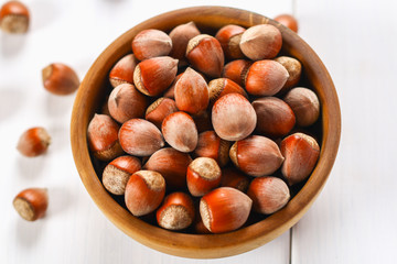 Hazelnut nuts in a wooden bowl on a white wooden table. Superfood.
