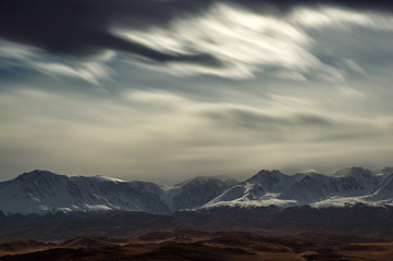 Obraz na płótnie Canvas Dark desert night steppe on a highland mountain plateau with ranges of snow peaks on a horizon under moon light Kurai Altai Mountains Siberia Russia