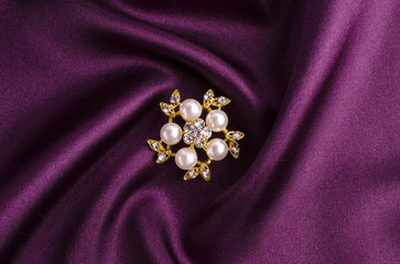 gold brooch flower with pearl isolated on silk