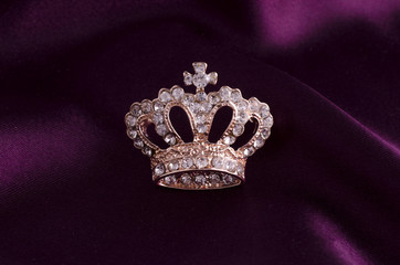 golden brooch crown isolated on white silk