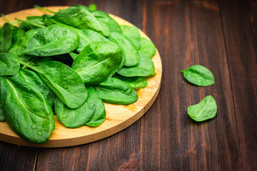 Fresh juicy spinach leaves on a wooden brown table. Natural products, greens, healthy food, vitamins.