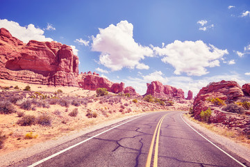 Retro toned picture of a scenic road, travel concept picture, Arches National Park in Utah, USA.