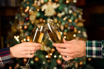 Cheers!Close up photo of two people holding glasses of shampagne on xmas.