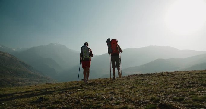 Hiking couple walking on trail. Healthy lifestyle hiker people walking in mountains. Young woman and man travel to honeymoon, steadycam shot