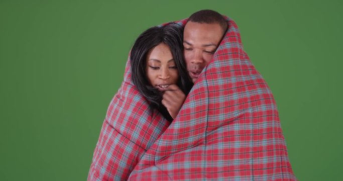 Black couple wrapped up in sleeping bag while camping on green screen. On green screen to be keyed or composited. 