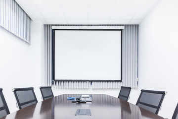 Meeting room with table chair and projector screen in modern office