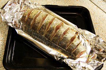 Fresh raw fish in spices in foil on a baking sheet is ready for cooking. Delicious dinner.