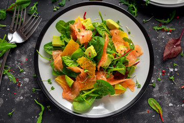 Fresh salmon salad with avocado, orange and green vegetables.