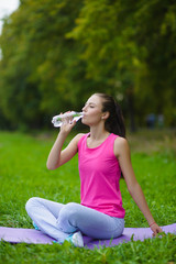 Beautiful fitness athlete woman resting drinking water outdoor