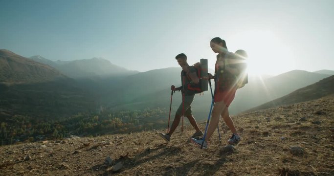 Hiking couple walking on trail. Healthy lifestyle hiker people walking in mountains. Young woman and man travel to honeymoon, steadycam shot