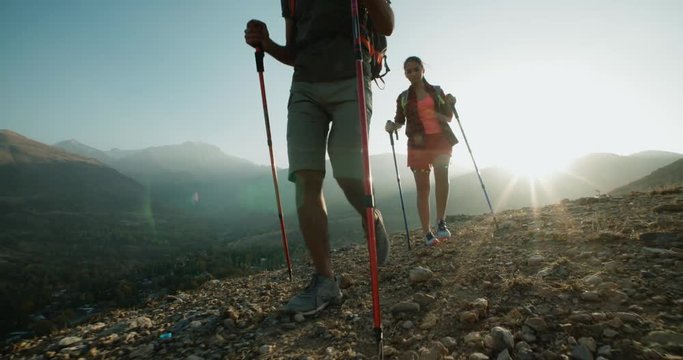 Hiking couple walking on trail. Healthy lifestyle hiker people walking in mountains. Young woman and man travel to honeymoon, steadycam shot