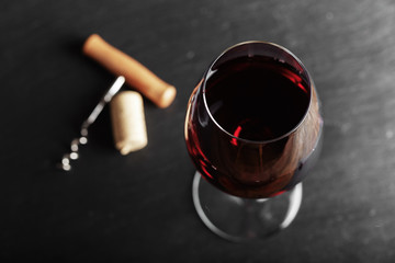wine glass of red wine with a corkscrew. On a black wooden background. with space for text