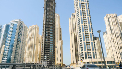 Fototapeta na wymiar Tall office and hotel buildings in sunny day in downtown Dubai, UAE. Skyscrapers in Dubai the view from the road