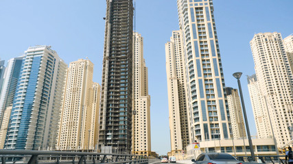 Fototapeta premium Tall office and hotel buildings in sunny day in downtown Dubai, UAE. Skyscrapers in Dubai the view from the road
