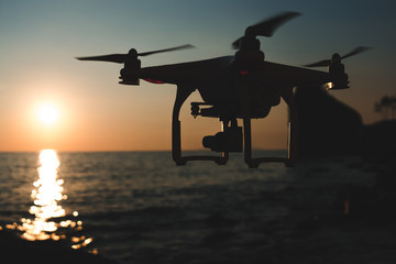 Fototapeta na wymiar The drone in the sunset sky. ocean wave mountains Close up of quadrocopter outdoors. concept for film maker wedding videography aerial photographer. equipment for vlog blog, old,