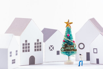 Miniature tiny people toys enjoy with christmas tree in the paper house town at christmas day isolated on white background with copy space.Theme Christmas day background.